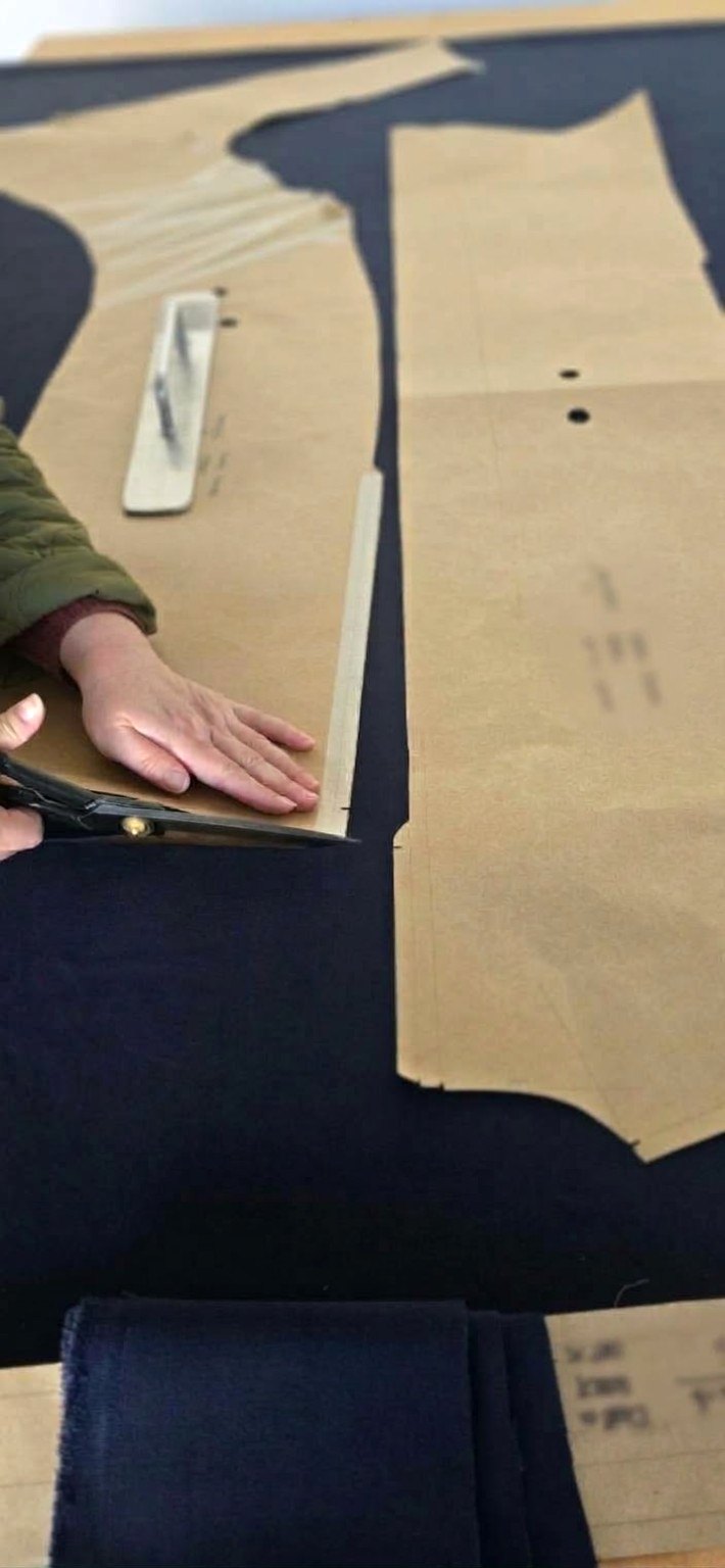 Hands cutting fabric around a garment pattern
