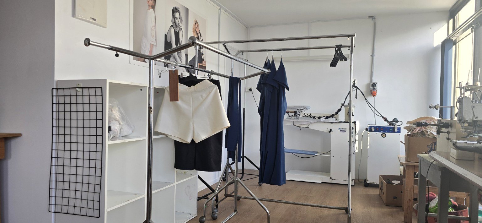 Garments hanging beside pressing and finishing equipment in the workshop